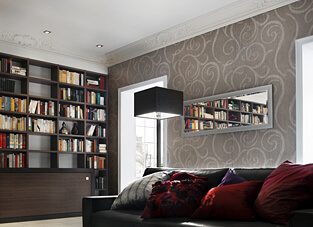 Ein Wohnzimmer im klassischen Stil mit einer dunkelbraunen Ledercouch und einer großen, eingebauten Bücherwand. Die Decke ist mit einem klassischen Deckenprofil versehen, das dem Raum eine elegante, historische Note verleiht.