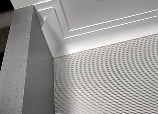 Wand-Ecke mit Deckenansicht. Linke Wand dunkelgrau, rechte Wand hellgrau. Weiße Decke mit moderne Stuckprofil.