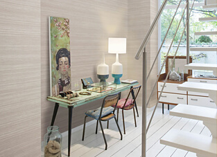 Ein heller Innenraum, dessen Wände mit einer Omexco-Tapete in Travertinoptik tapeziert sind. Die Tapete weist ein horizontales Streifendesign in hellen, beigen oder hellgrauen Naturtönen auf. Rechts führt eine weiße Holztreppe nach oben, links steht ein Vintage-Schreibtisch, der als Schminktisch dient, mit einer modernen, weiß-türkisen Lampe.