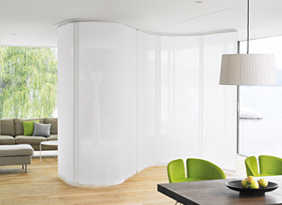 Moderner Ess- und Wohnbereich getrennt von einem gebogenen Flächenvorhang-System mit Elektroantrieb.
