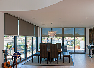 Gemütlicher Essbereich umgeben von einer großen Fensterfront mit Sandfarbenen Elektrozug-Rollos.