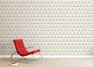 Eine Wand, die mit der KT Tapete in einem modernen, dreidimensionalen (3-D) Design verkleidet ist. Die Tapete besteht aus einem wiederholten Pyramidenmuster in einem hellen, cremeweißen oder hellgrauen Farbton, das durch Licht und Schatten einen 3D-Effekt erzeugt. Davor steht ein roter, moderner Schaukelstuhl auf einem beigefarbenen Teppich.
