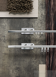 Designbeispiel von zwei Gardinenschienen mit geraden Endstücken, montiert auf einer grau melierten Wand mit großen rechteckigen Haltern. Oben Silber glänzend mit drei montierten Gleitern, unten matt Silber mit drei Montierten Gleitern und Gardinenhaken daran.