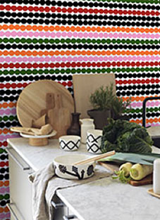 Designbeispiel einer Tapete von Marimekko Vol.5-02. Wand mit bunter Tapete, gepunktete Linien in verschiedenen Farben. Davor eine Küchenzeile mit Brettern, Gemüse und Geschirr darauf.